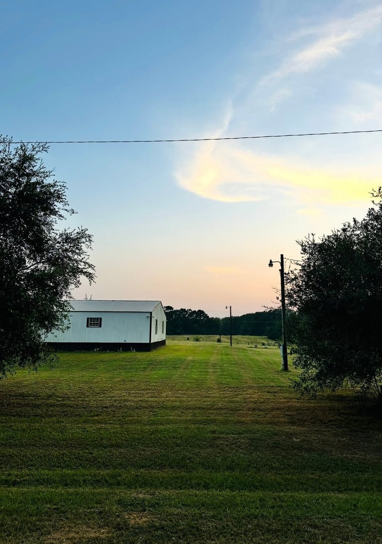 White trailer on green rural property at sunset with power lines, surrounded by trees